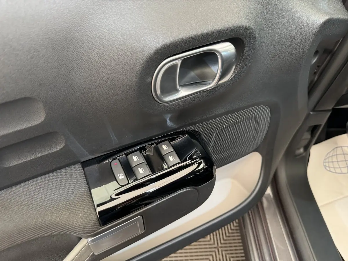 Gros plan sur la porte avant gauche grise d'une Citroën C3 2020, avec commandes de vitres et poignée argentée.