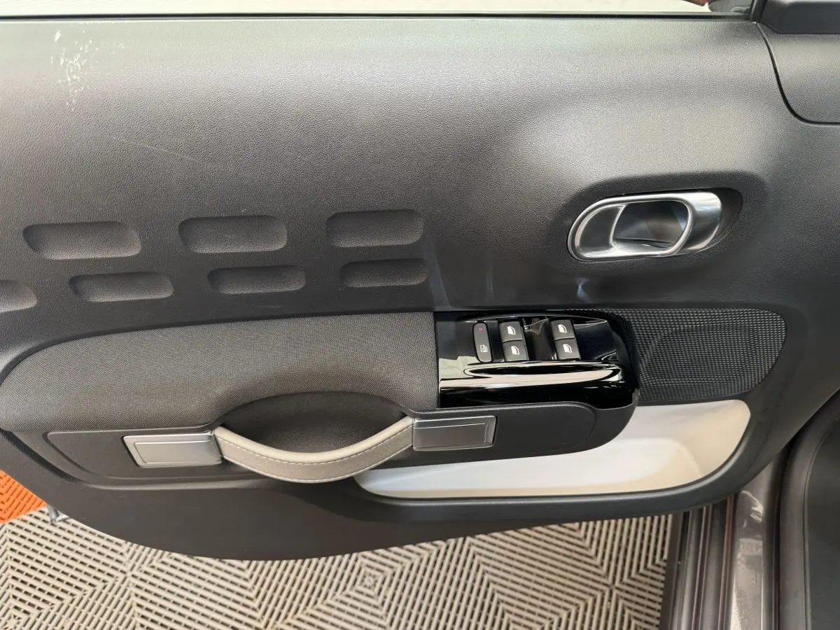 Vue rapprochée de la porte avant gauche gris foncé de la Citroën C3 avec commandes de vitres et poignée intégrée.