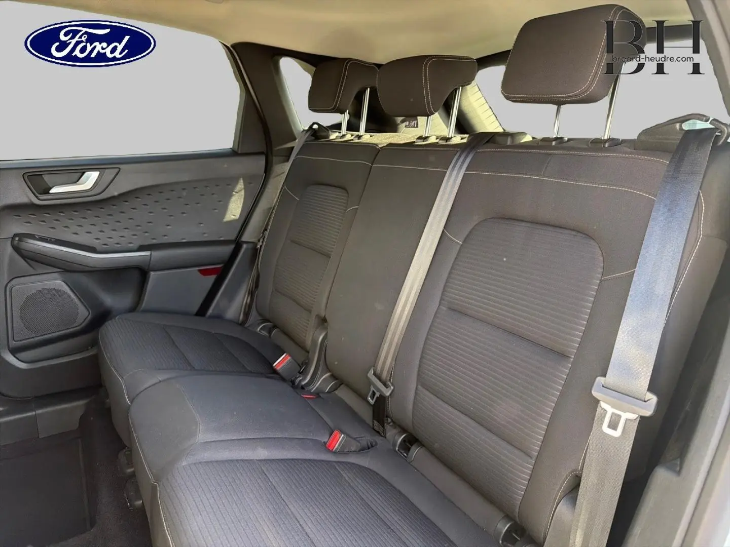 Vue intérieure côté droit sur la banquette arrière noire du Ford Kuga 1.5 EcoBlue 2021 avec ceintures de sécurité visibles.
