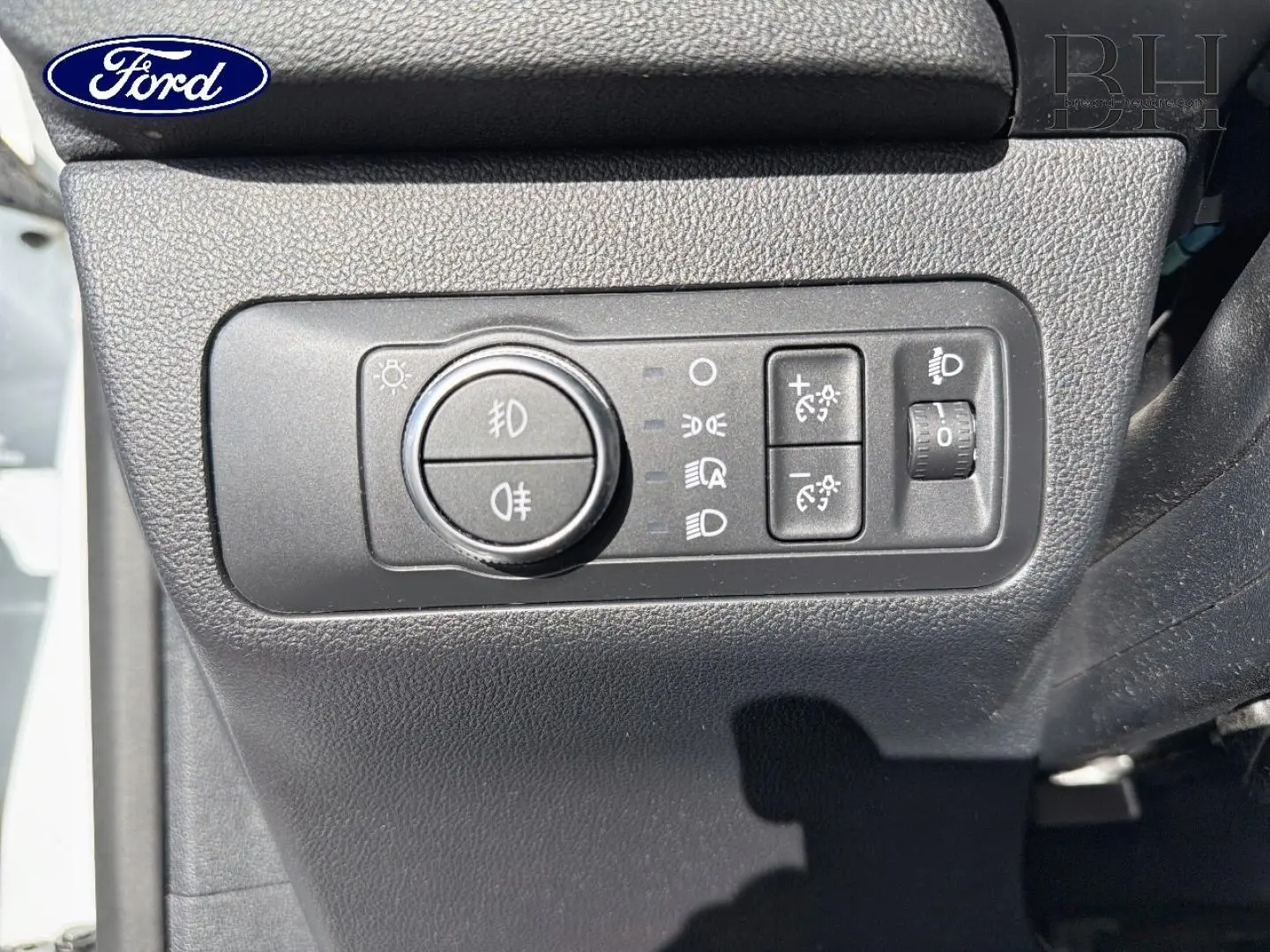 Gros plan sur le panneau de commande des phares et réglages lumineux du Ford Kuga blanc Glacier, côté gauche du tableau de bord.