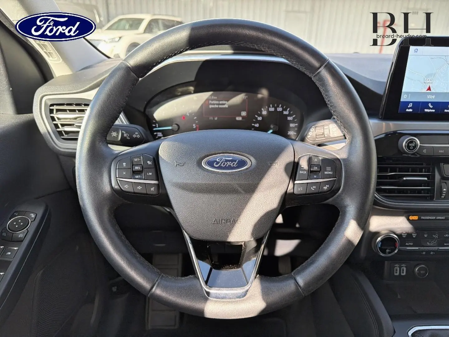 Vue intérieure centrée sur le volant cuir multifonction du Ford Kuga 1.5 EcoBlue 2021 avec tableau de bord et écran tactile.