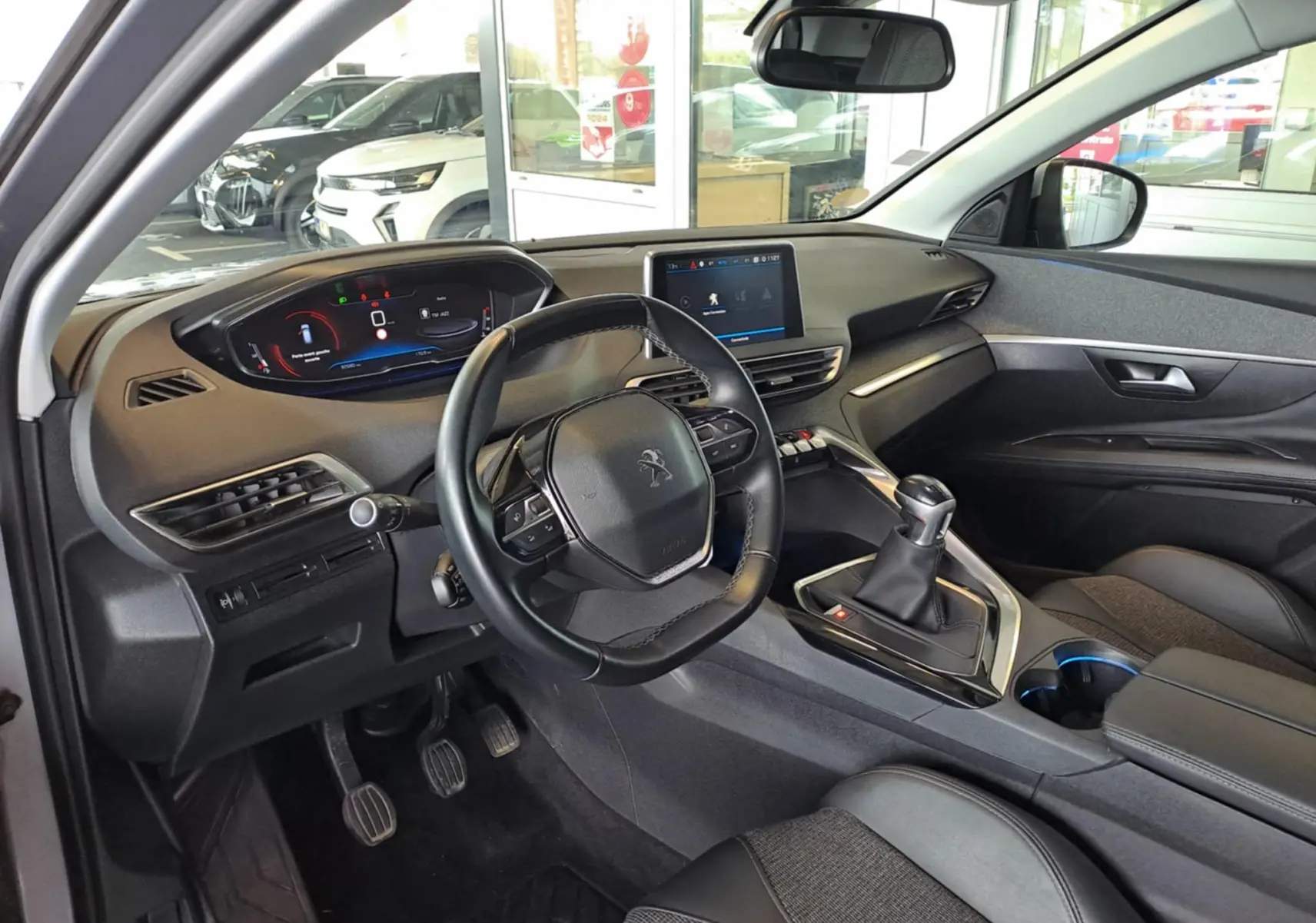 Vue intérieure côté conducteur du Peugeot 3008 gris Artense 2019, avec tableau de bord numérique et boîte manuelle.