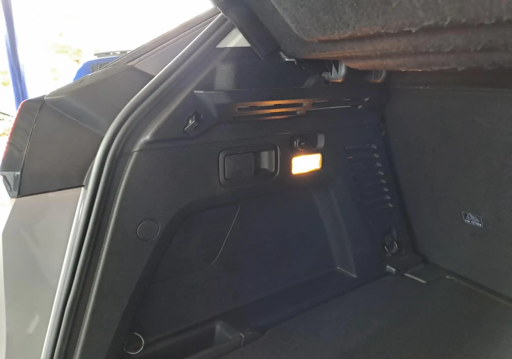 Vue intérieure du coffre du Peugeot 3008 gris Artense, mettant en valeur un éclairage latéral et des rangements intégrés.