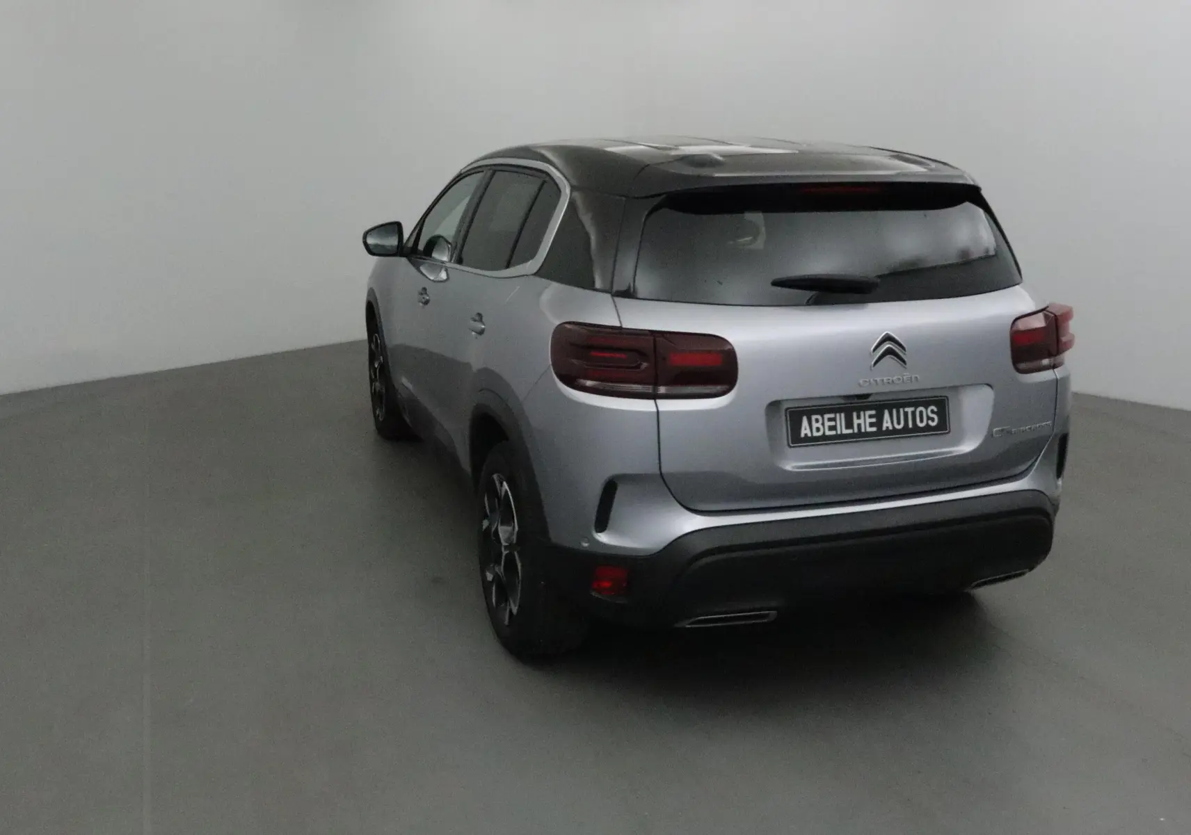 Vue 3/4 arrière droite du Citroën C5 Aircross gris Artense avec toit noir et feux arrière LED dans un studio.