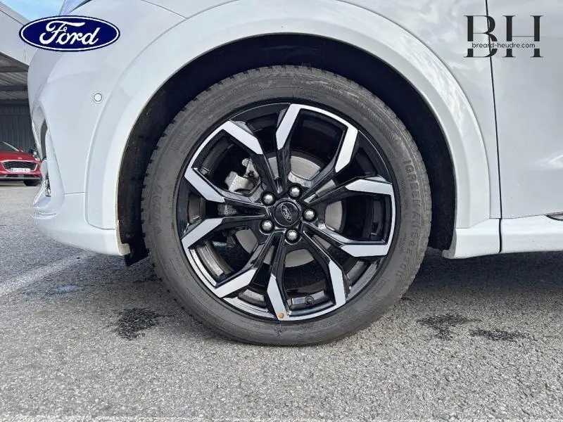 Gros plan sur la jante alu noire et argentée du côté avant gauche d'un Ford Puma Blanc Glacier 2022.