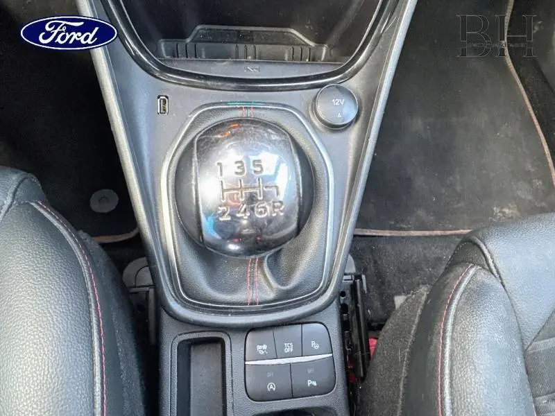 Gros plan sur le levier de vitesses manuel noir avec coutures rouges dans l'habitacle du Ford Puma blanc Glacier 2022.