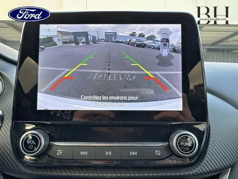 Vue de l'écran tactile du Ford Puma blanc glacier montrant la caméra de recul avec guidage coloré et capteurs de stationnement.