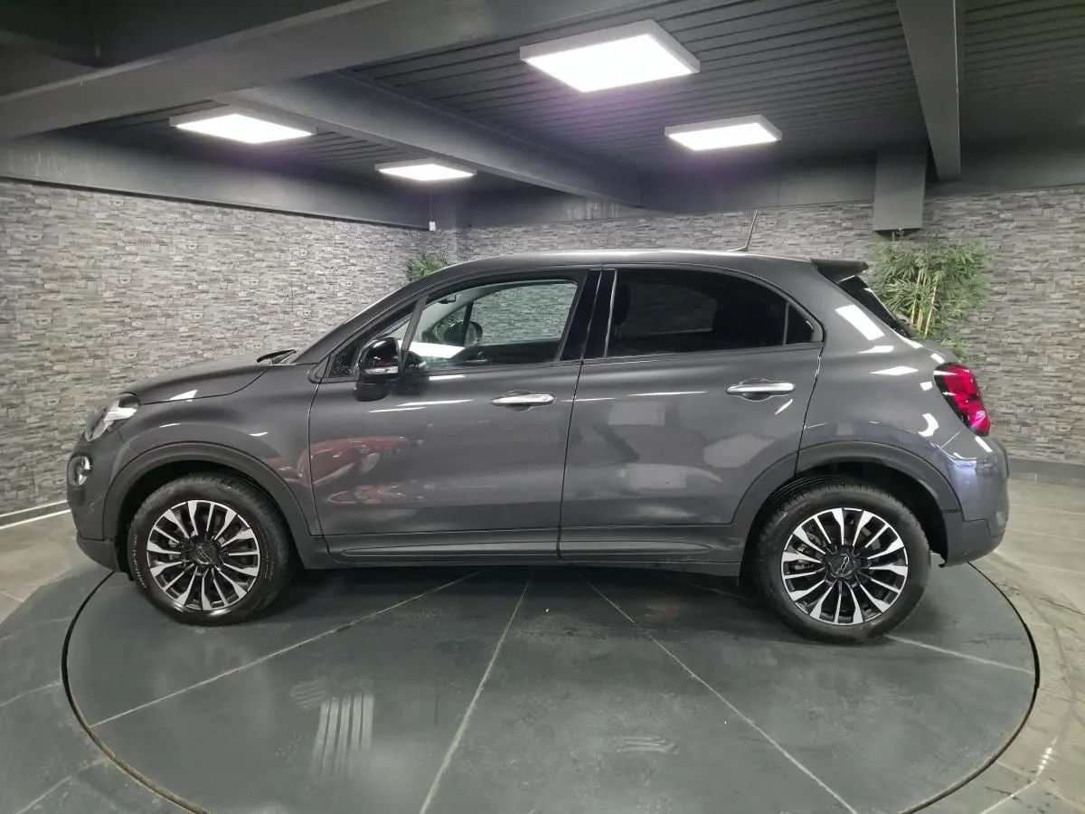 Fiat 500X gris vue de profil côté gauche, avec jantes alliage 17 pouces et vitres surteintées.