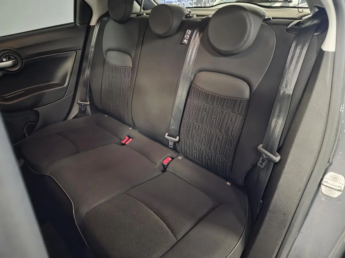 Vue intérieure sur la banquette arrière noire de la Fiat 500X 2024 avec monogramme FIAT sur les dossiers.