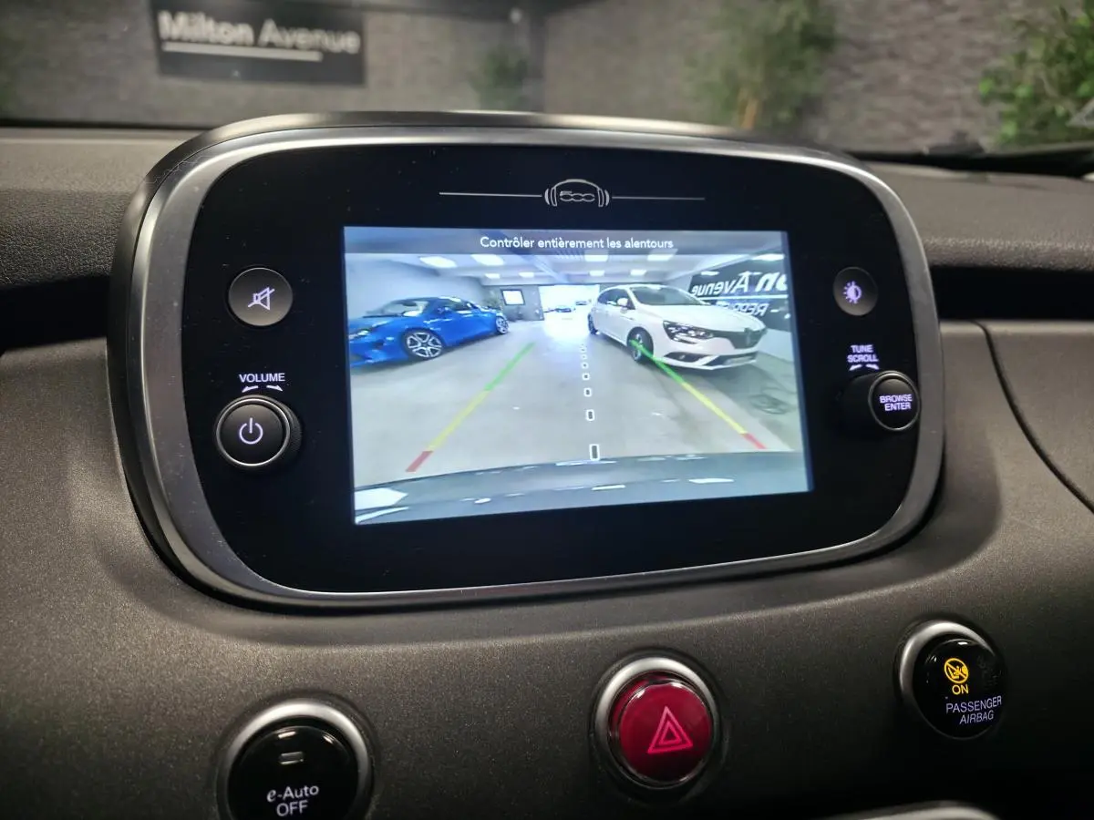 Écran central montrant la caméra de recul du Fiat 500X gris, vue arrière en intérieur de garage.