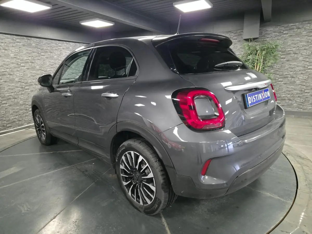 Fiat 500X gris métallisé vue 3/4 arrière droit, avec jantes alliage 17 pouces et feux arrière LED distinctifs.