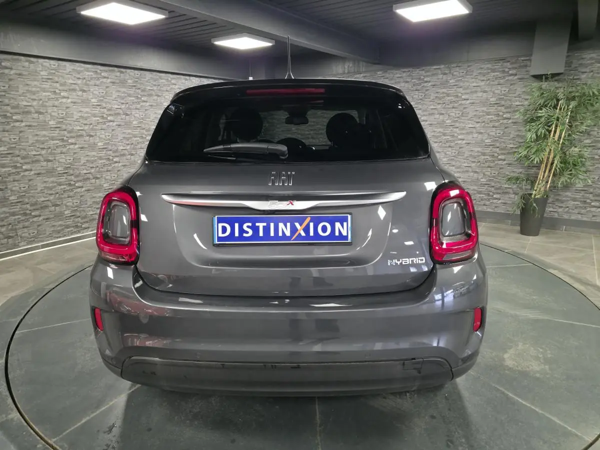 Vue arrière d'une Fiat 500X gris métallisé 2024 avec feux arrière LED et logo Hybrid visible.