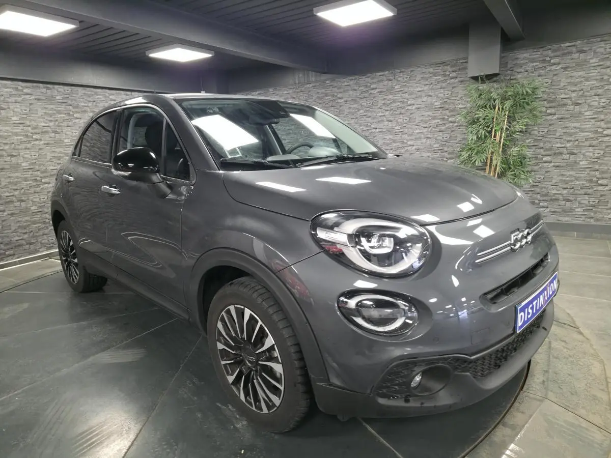 Fiat 500X gris métallisé vue 3/4 avant droit, avec jantes alliage 17 pouces et projecteurs LED distinctifs.