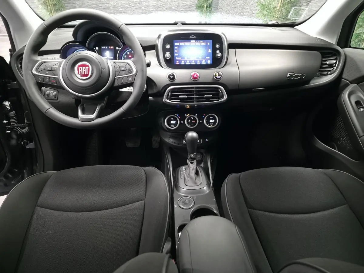 Intérieur noir de la Fiat 500X 2024 vu de face, avec tableau de bord gris titane et écran tactile central.