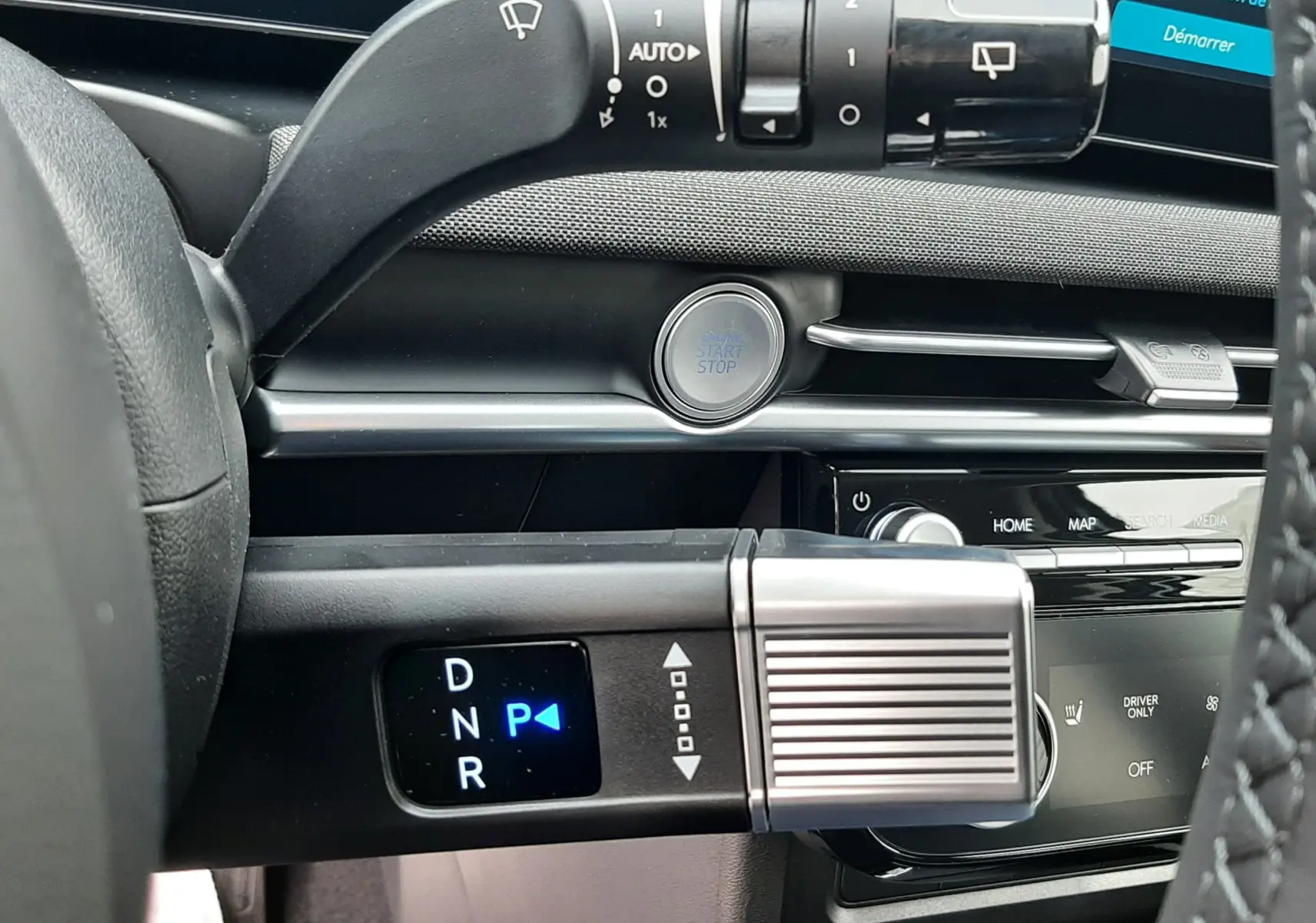 Détail intérieur du Hyundai Tucson 2025 montrant la commande de boîte automatique et le bouton start/stop sur tableau de bord noir.