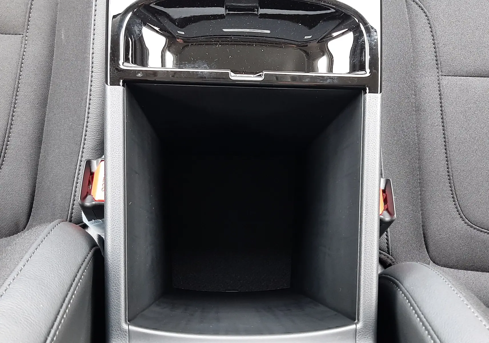 Vue plongeante sur le rangement central ouvert de l’habitacle gris foncé du Hyundai Tucson 2025, avec accoudoirs en tissu.