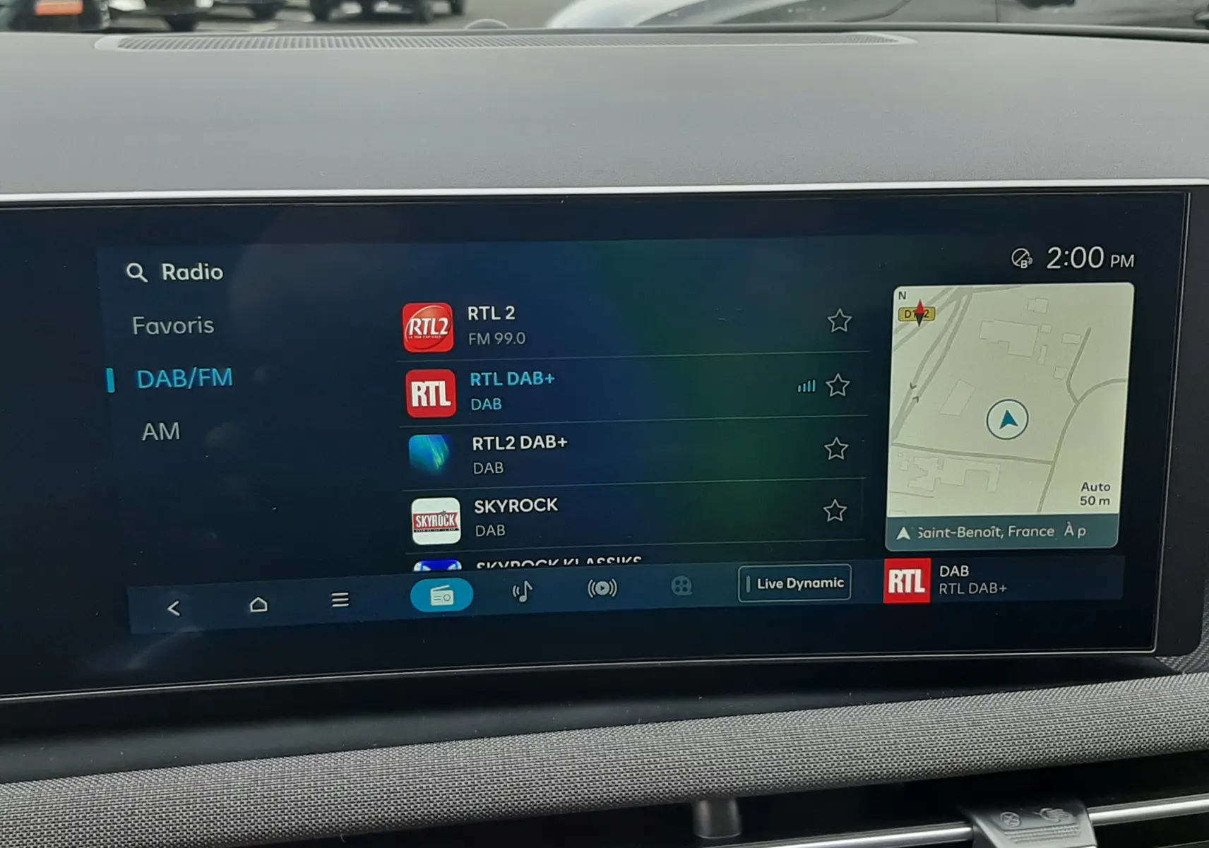 Affichage de l'écran multimédia du Hyundai Tucson 2025 en intérieur, montrant la sélection radio DAB/FM avec carte GPS.