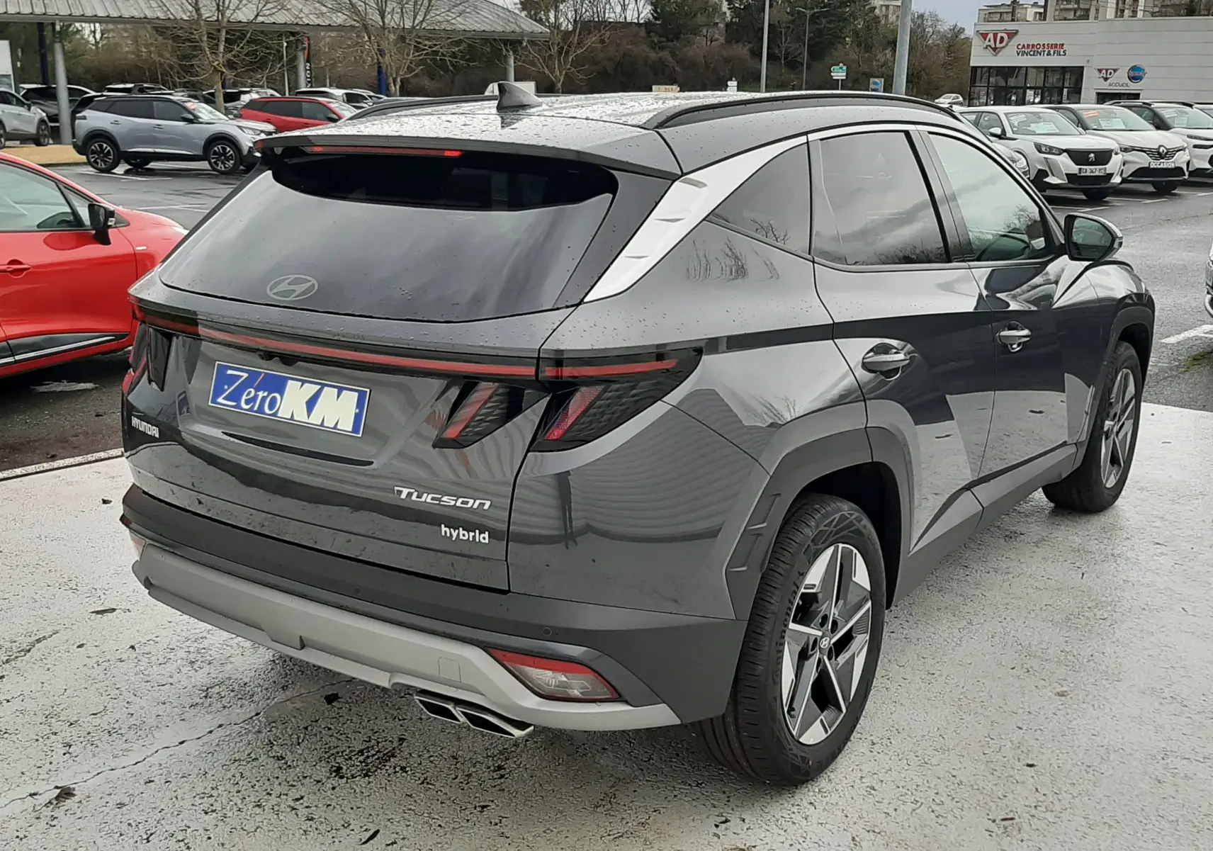Vue 3/4 arrière droite du Hyundai Tucson 2025 gris Ecotronic, avec hayon électrique et feux arrière LED distinctifs.
