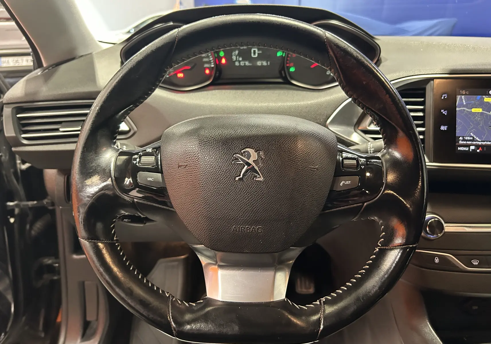 Vue rapprochée du volant en cuir noir du Peugeot 308 SW 2018, avec tableau de bord et écran GPS visibles.