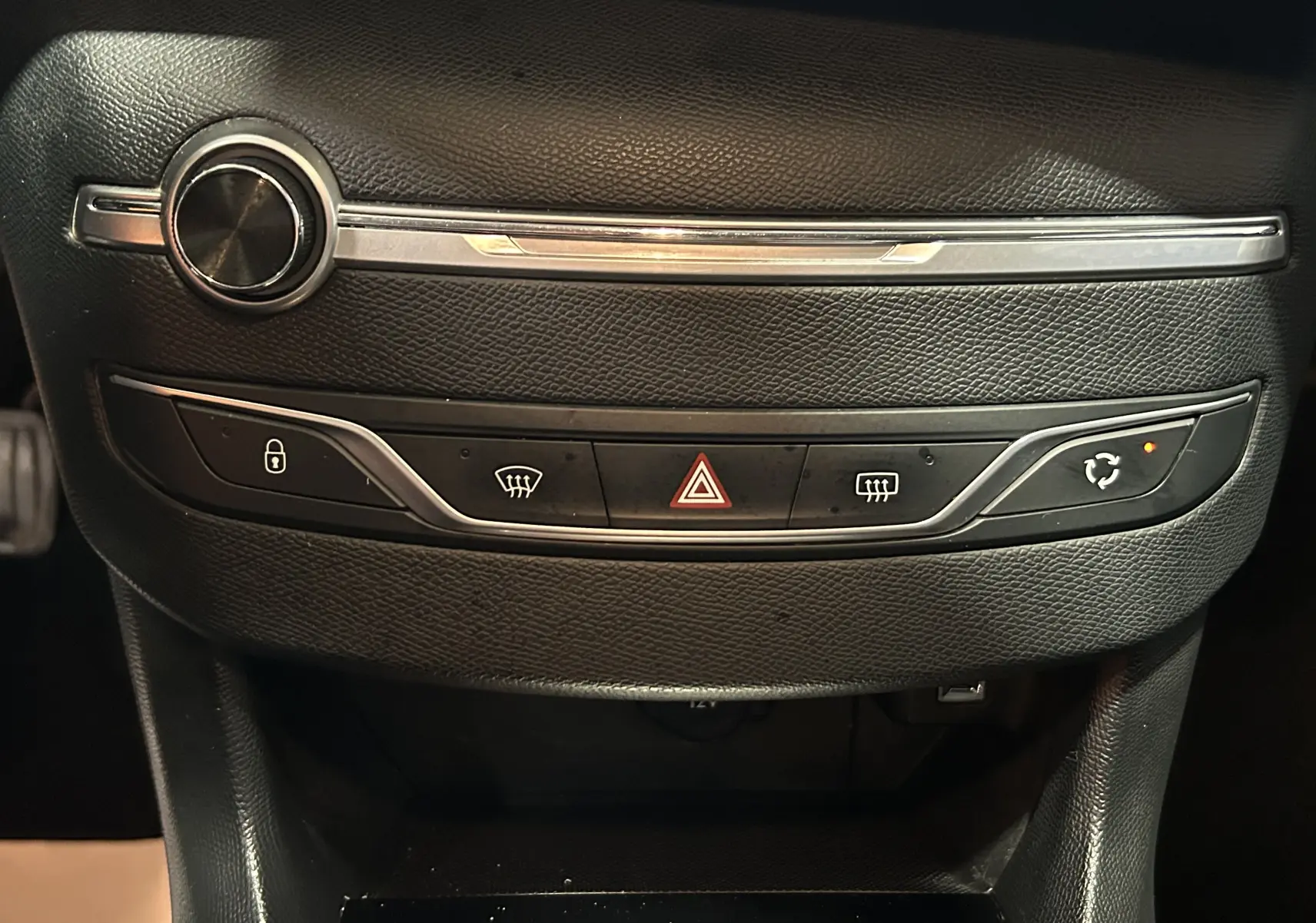 Détail du tableau de bord noir de la Peugeot 308 SW 2018, avec commandes de verrouillage, feux et recyclage d'air.