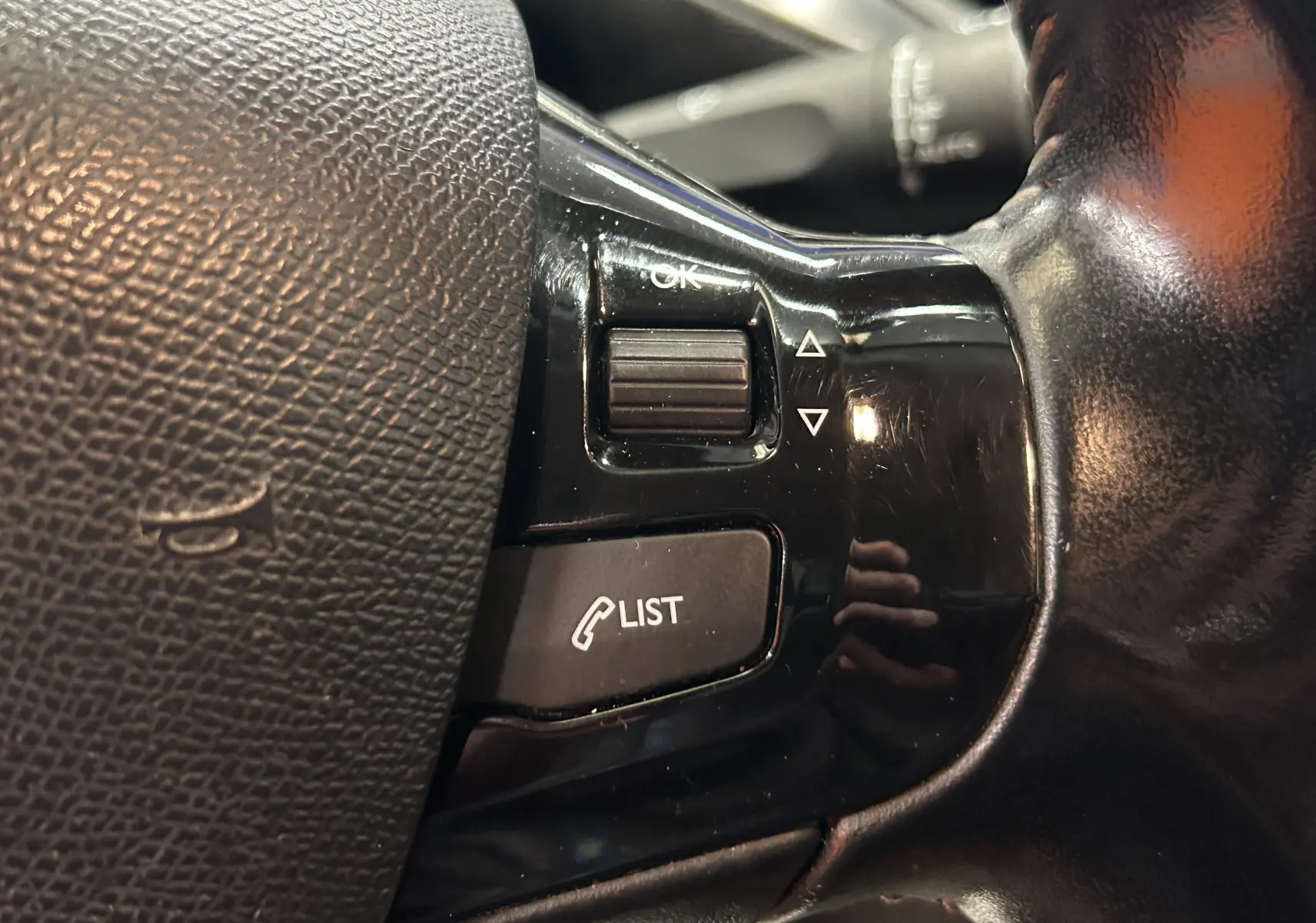 Gros plan sur les commandes noires au volant de la Peugeot 308 SW, boutons pour liste d'appels et navigation menu.