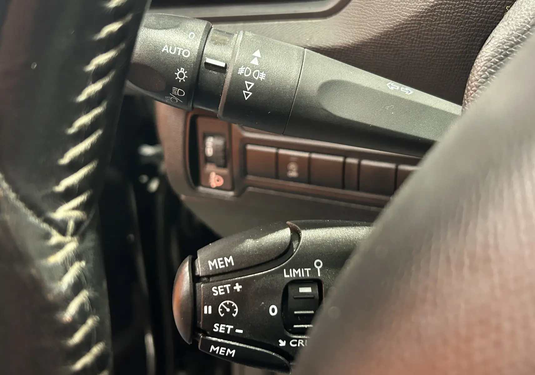 Gros plan sur la commande de régulateur de vitesse noire, avec détails des boutons, sur le volant d’un Peugeot 308 SW noir.