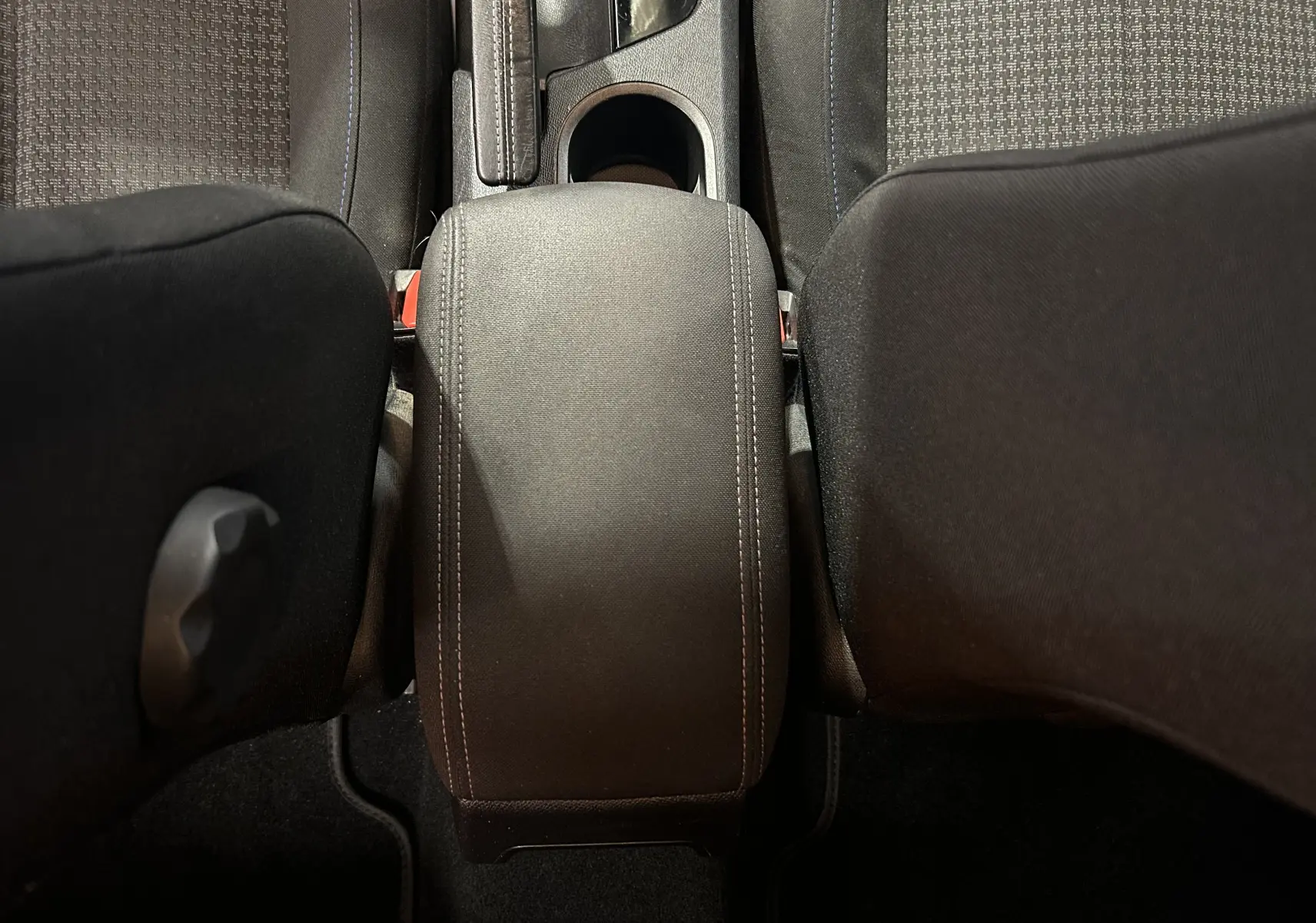 Vue plongeante sur l'accoudoir central noir et les sièges tissu gris du Peugeot 308 SW 2018.