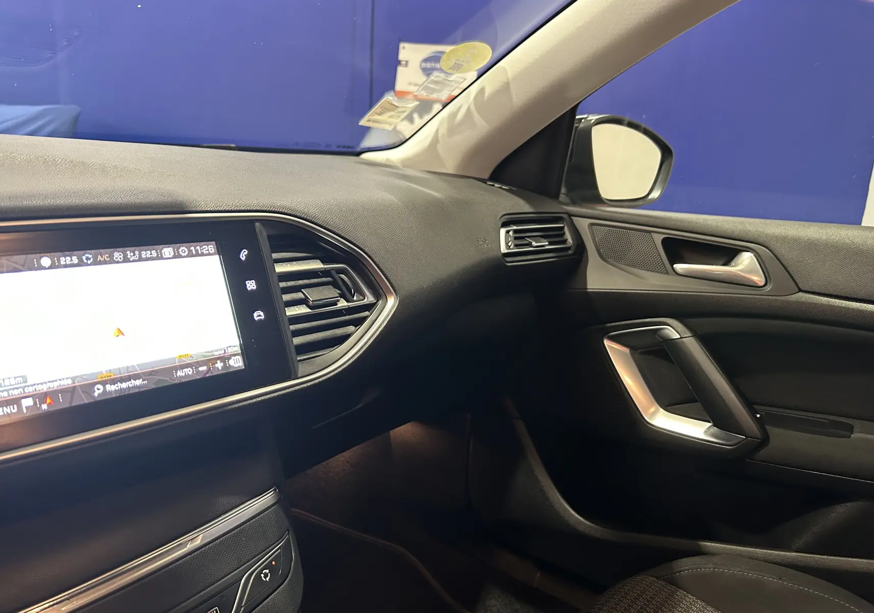 Intérieur côté passager de la Peugeot 308 SW noire, avec tableau de bord et écran GPS allumé visible de profil droit.