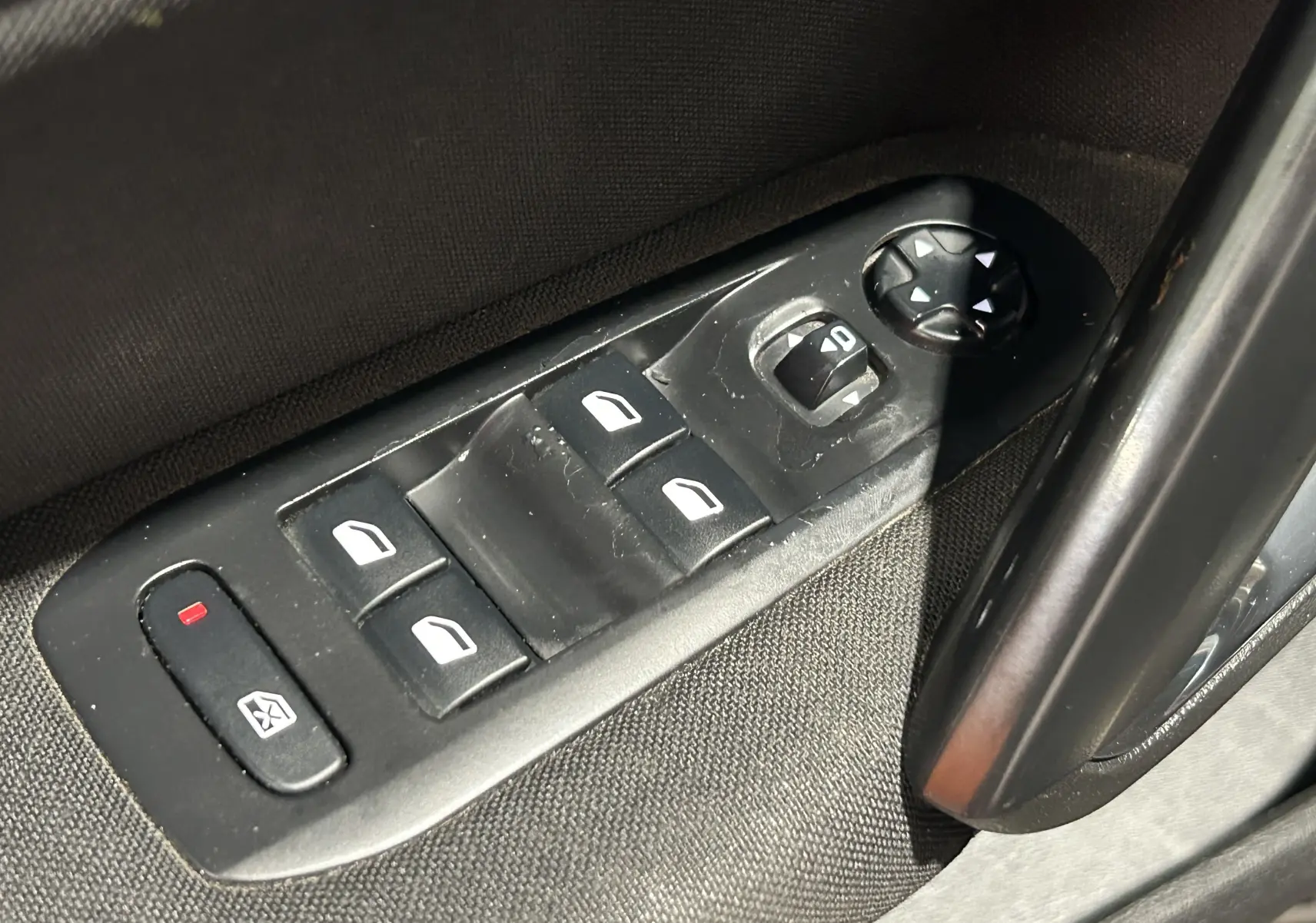 Gros plan sur les commandes de lève-vitres et rétroviseurs côté conducteur d’une Peugeot 308 SW noire de 2018.