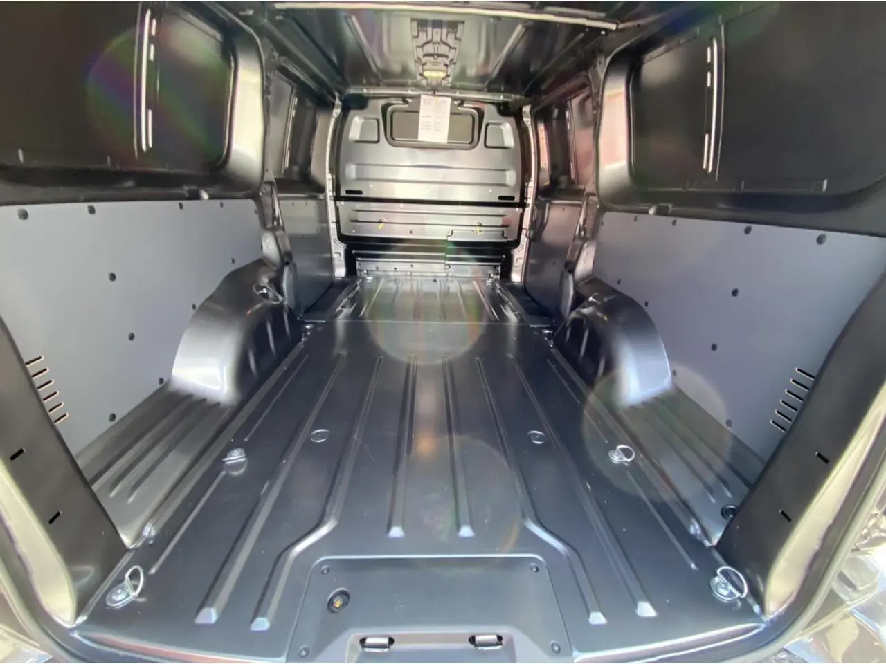 Vue intérieure arrière du Peugeot Expert Fourgon gris platinium, montrant l'espace de chargement tôlé et les parois latérales renforcées.