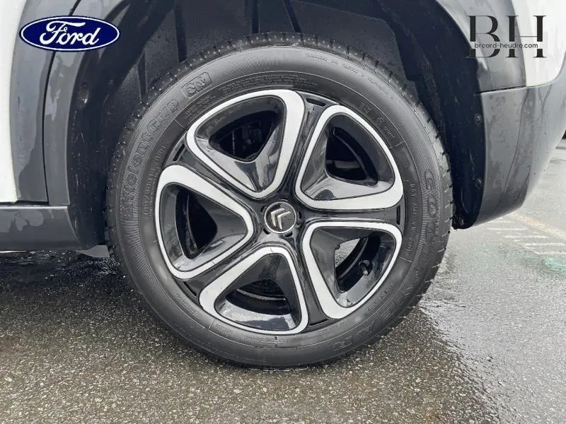 Gros plan sur la roue avant droite d'une Citroën C3 Aircross blanche avec jante noire et argentée au design distinctif.