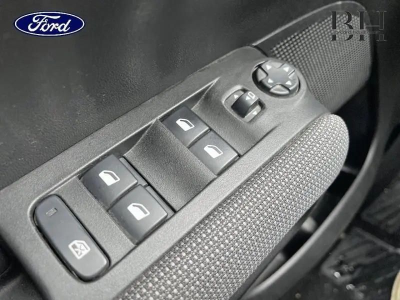 Panneau de commandes des vitres électriques côté conducteur avec tissu gris, détail intérieur d'une voiture non identifié.