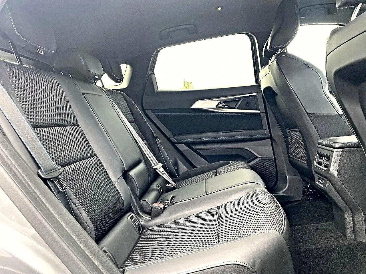 Vue intérieure côté droit de la banquette arrière noire en tissu et alcantara du Renault Austral gris schiste, avec accoudoirs et aérateurs.