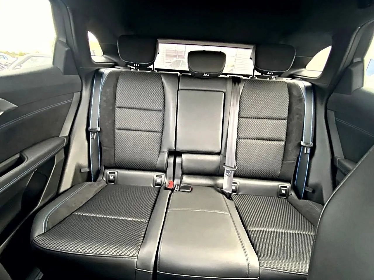 Vue arrière intérieure montrant la banquette noire en tissu carbone et alcantara avec surpiqûres bleues du Renault Austral 2026.