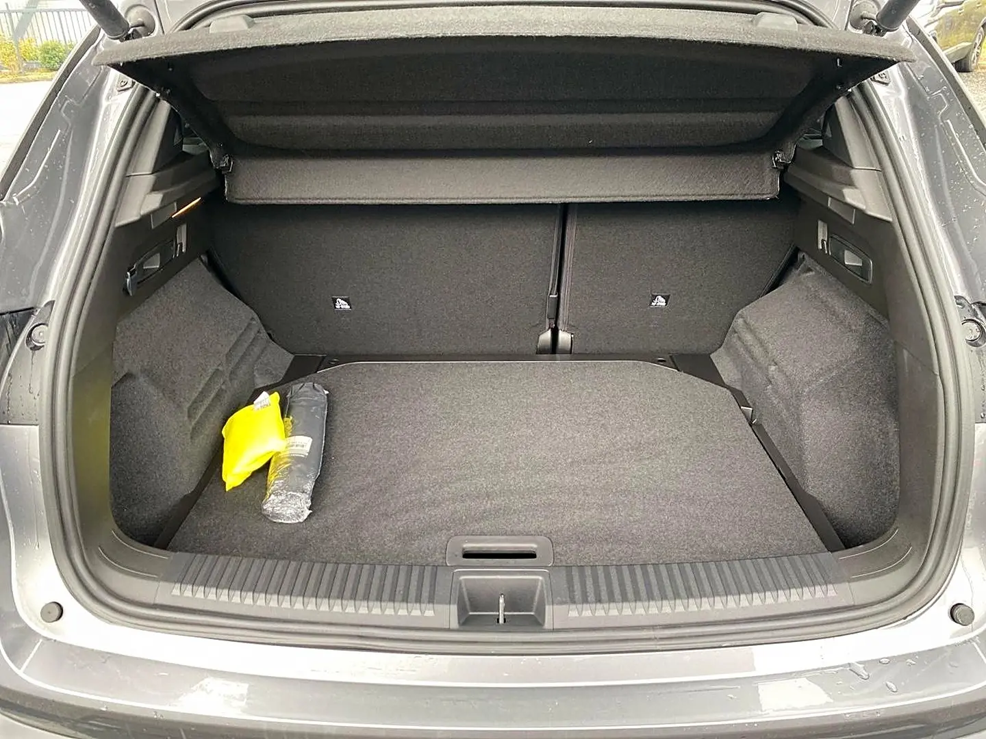 Coffre ouvert vu de l'arrière d'un Renault Austral gris schiste, avec tapis et accessoires de sécurité visibles.