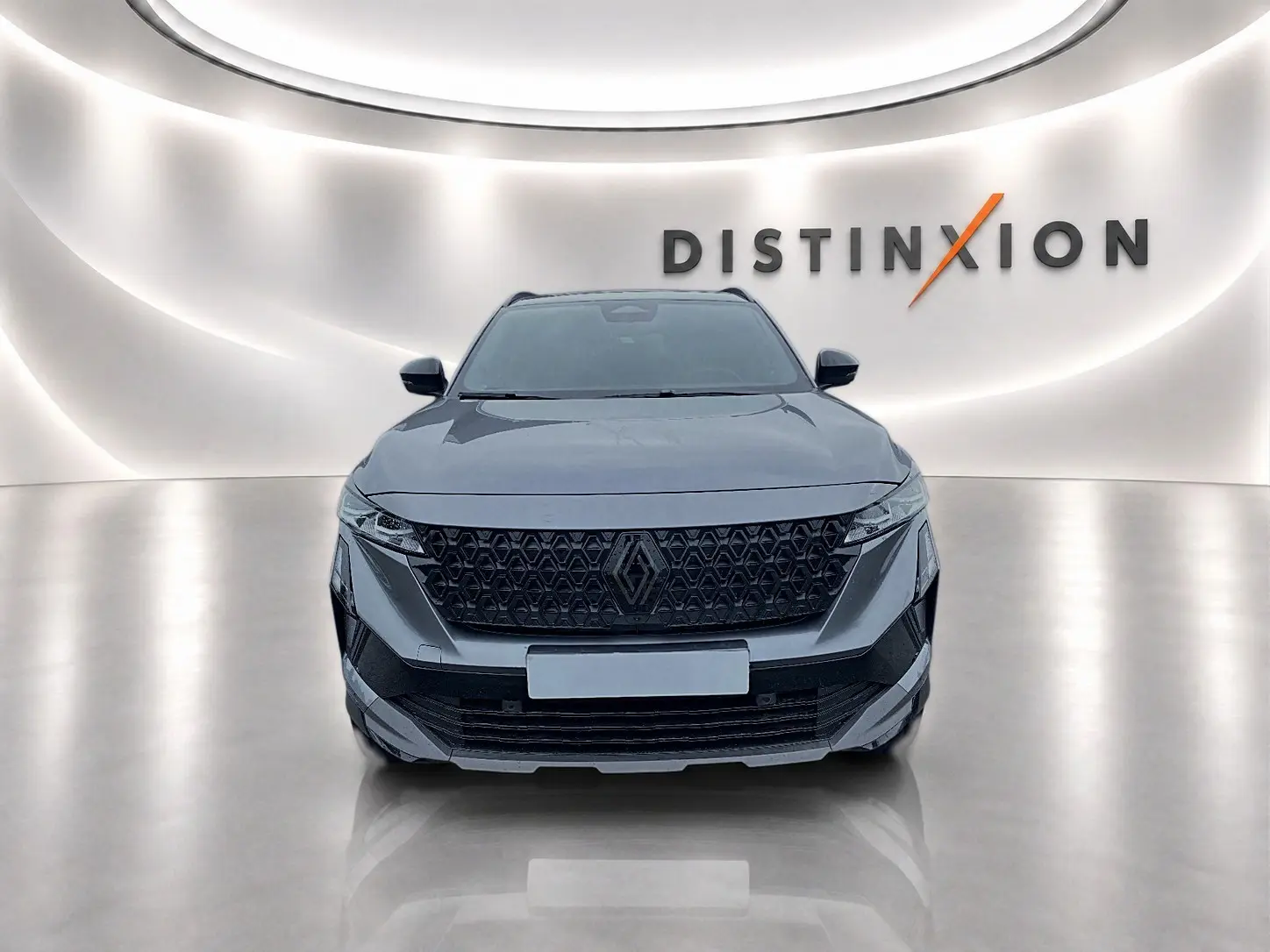 Vue frontale d'un Renault Austral gris schiste avec calandre noire et logo central dans un showroom lumineux.