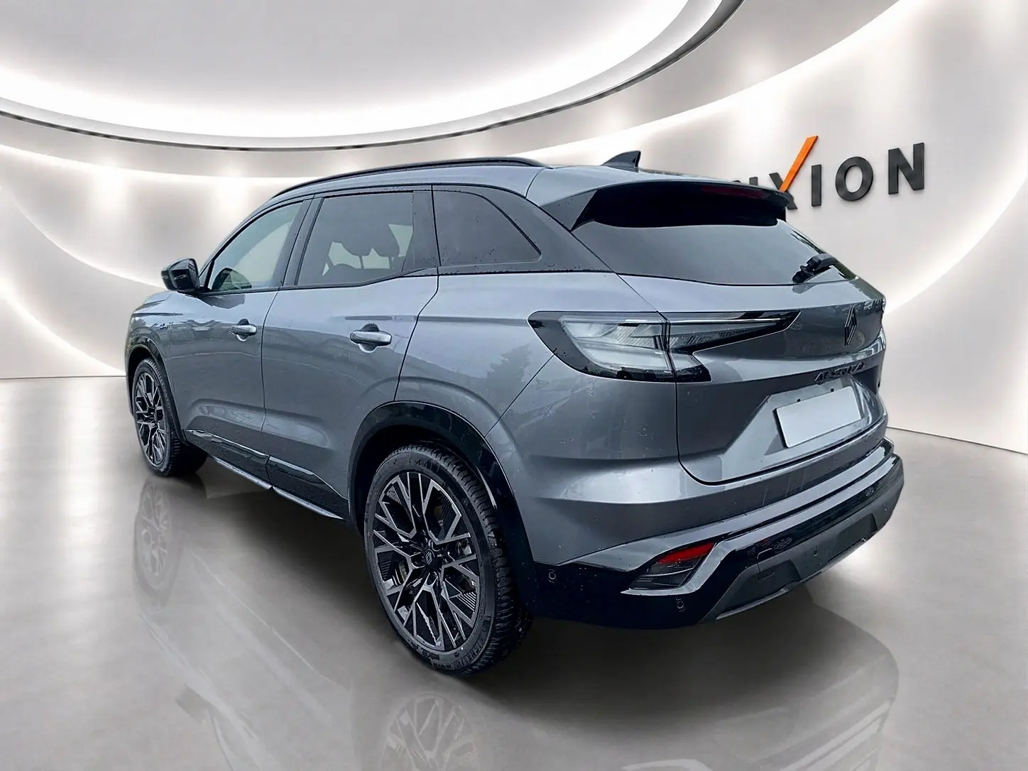 Vue 3/4 arrière droite du Renault Austral gris schiste avec jantes alu et toit noir brillant dans un showroom moderne.