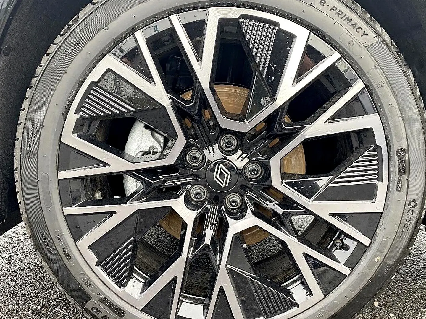 Gros plan sur la jante alu bicolore noire et argentée du Renault Austral gris schiste, avec logo Renault central.