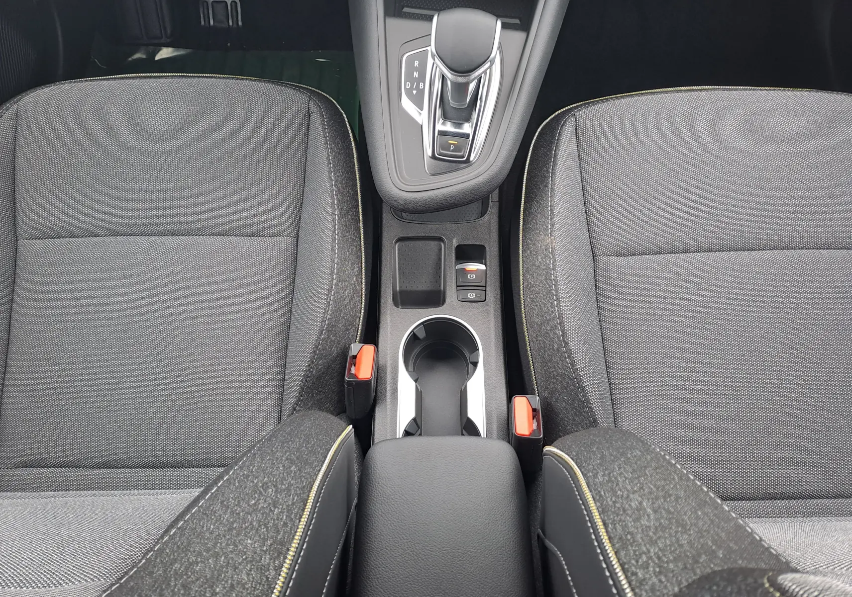 Vue plongeante sur la console centrale et les sièges en tissu gris avec surpiqûres jaunes de la Renault Symbioz 2025.