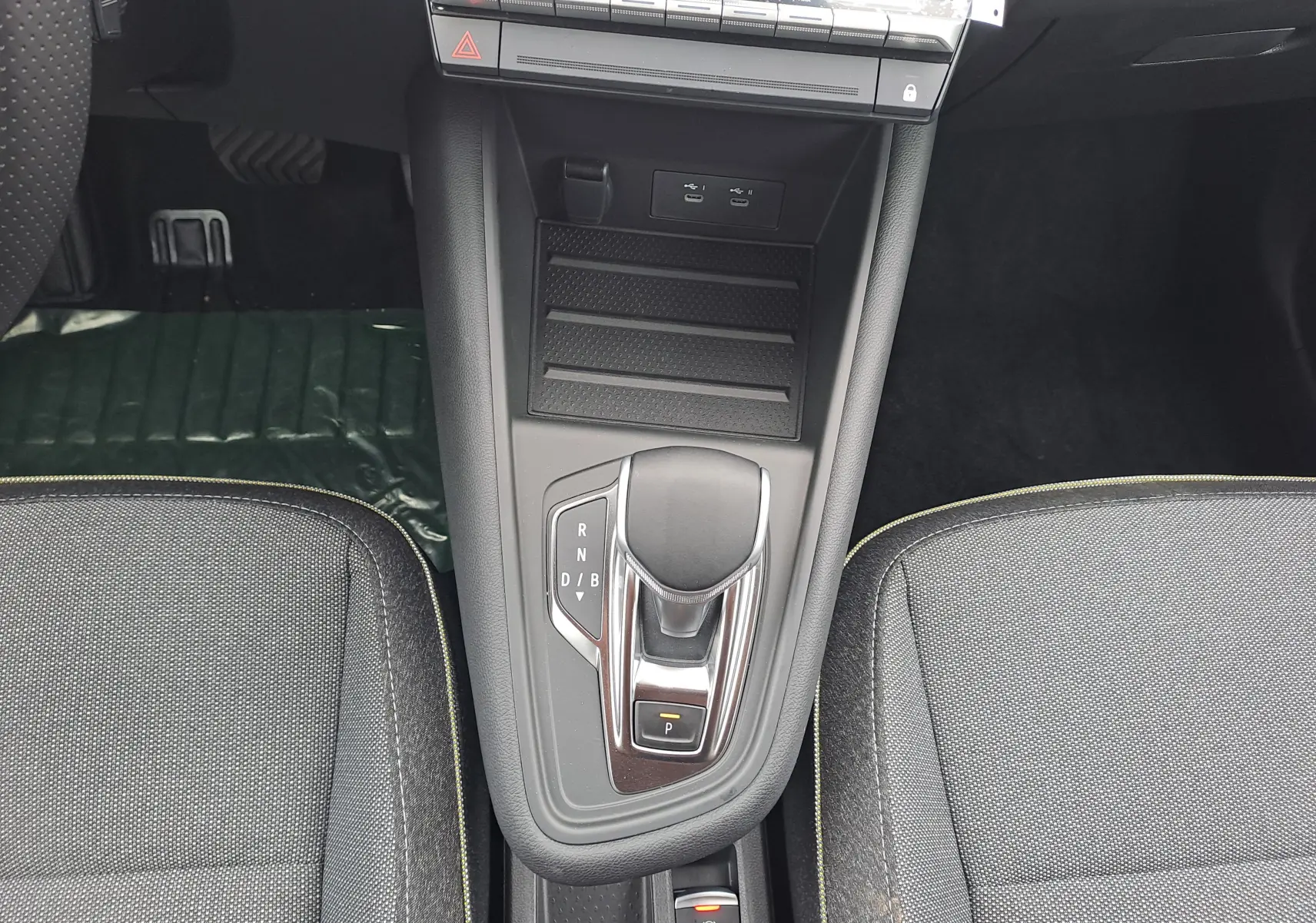 Vue plongeante sur la console centrale de la Renault Symbioz 2025, avec levier de boîte auto et sièges tissu gris.