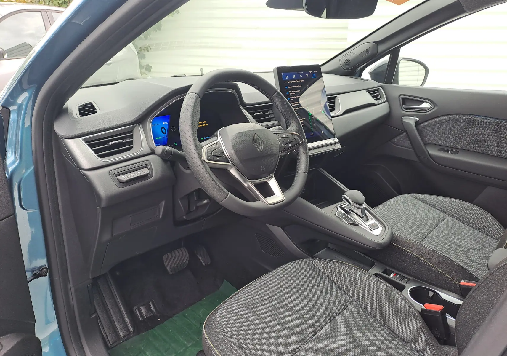 Intérieur avant droit de la Renault Symbioz bleu mercure, volant multifonction, écran tactile vertical et sellerie Techno grise.