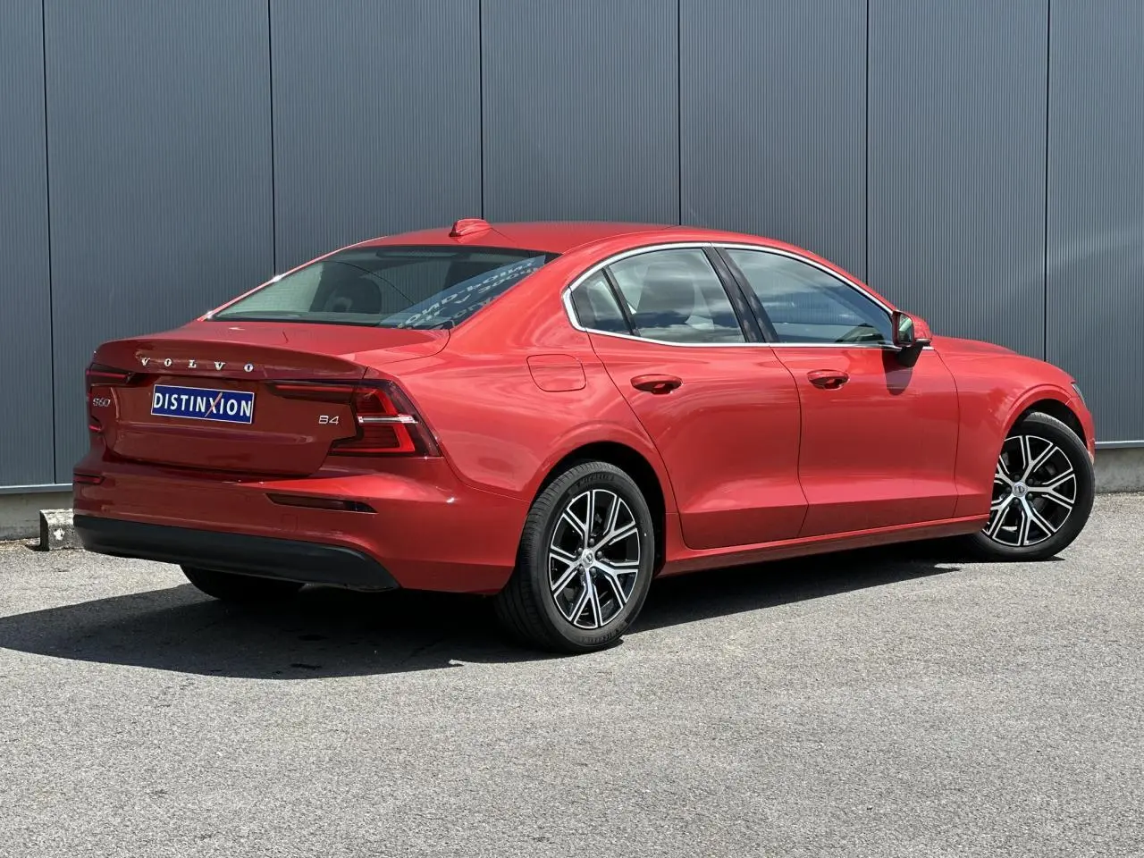 Vue 3/4 arrière droite d'une Volvo S60 B4 rouge Fusion avec jantes alliage 17 pouces et contours de fenêtres chromés.