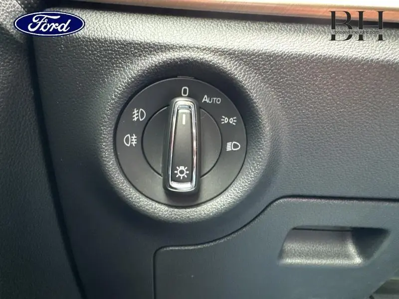 Gros plan sur le bouton de commande des phares dans l'habitacle noir d'une Skoda Kamiq gris graphite de 2023.