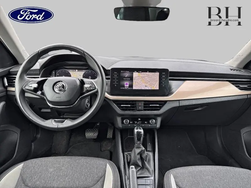 Tableau de bord et volant cuir noir de la Skoda Kamiq 1.0 TSI Style 2023 vus de face avec écran tactile et inserts bois clair.