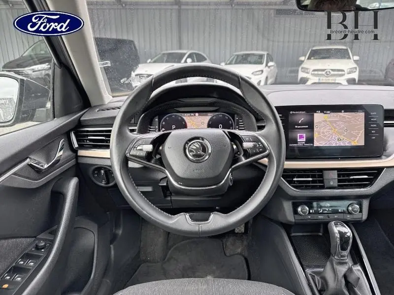 Vue intérieure centrée sur le volant cuir multifonction d'une Skoda Kamiq 2023, avec écran tactile et tableau de bord numérique.