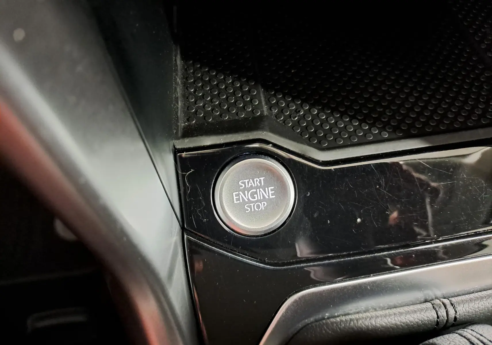 Bouton start/stop moteur en gros plan sur la console noire brillante du Volkswagen T-Roc 2024.
