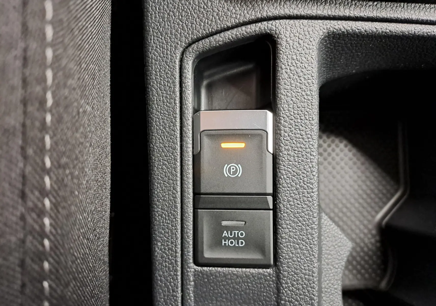 Gros plan sur la commande de frein à main électronique et fonction Auto Hold dans un Volkswagen T-Roc 2024.