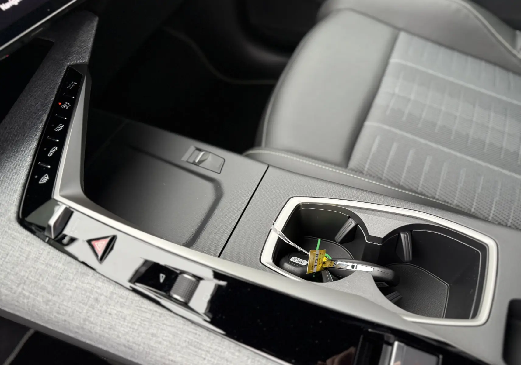 Gros plan sur la console centrale et porte-gobelets du Peugeot 3008 Hybrid 2025 avec sellerie grise et finitions modernes.