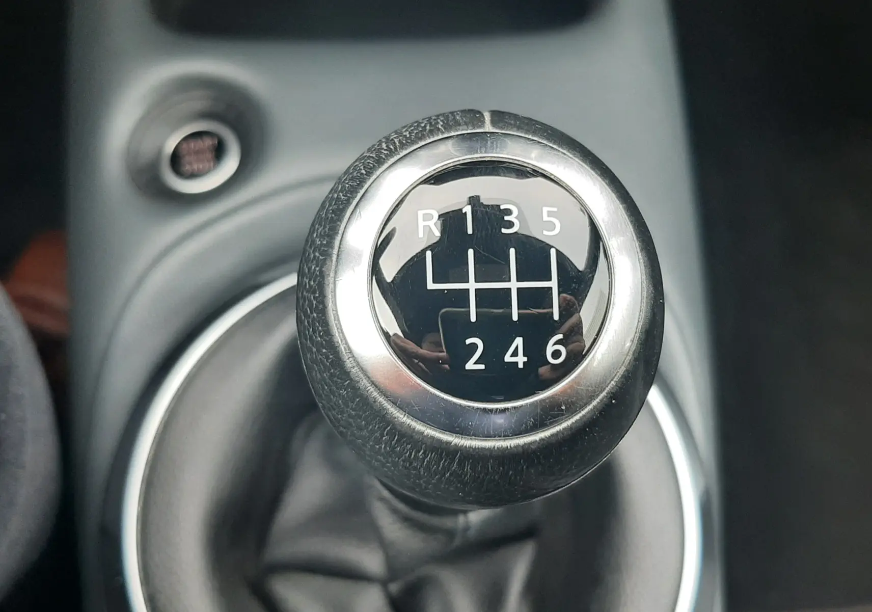 Gros plan sur le levier de vitesse manuel noir et chrome du Nissan Juke gris, montrant les six rapports et la marche arrière.