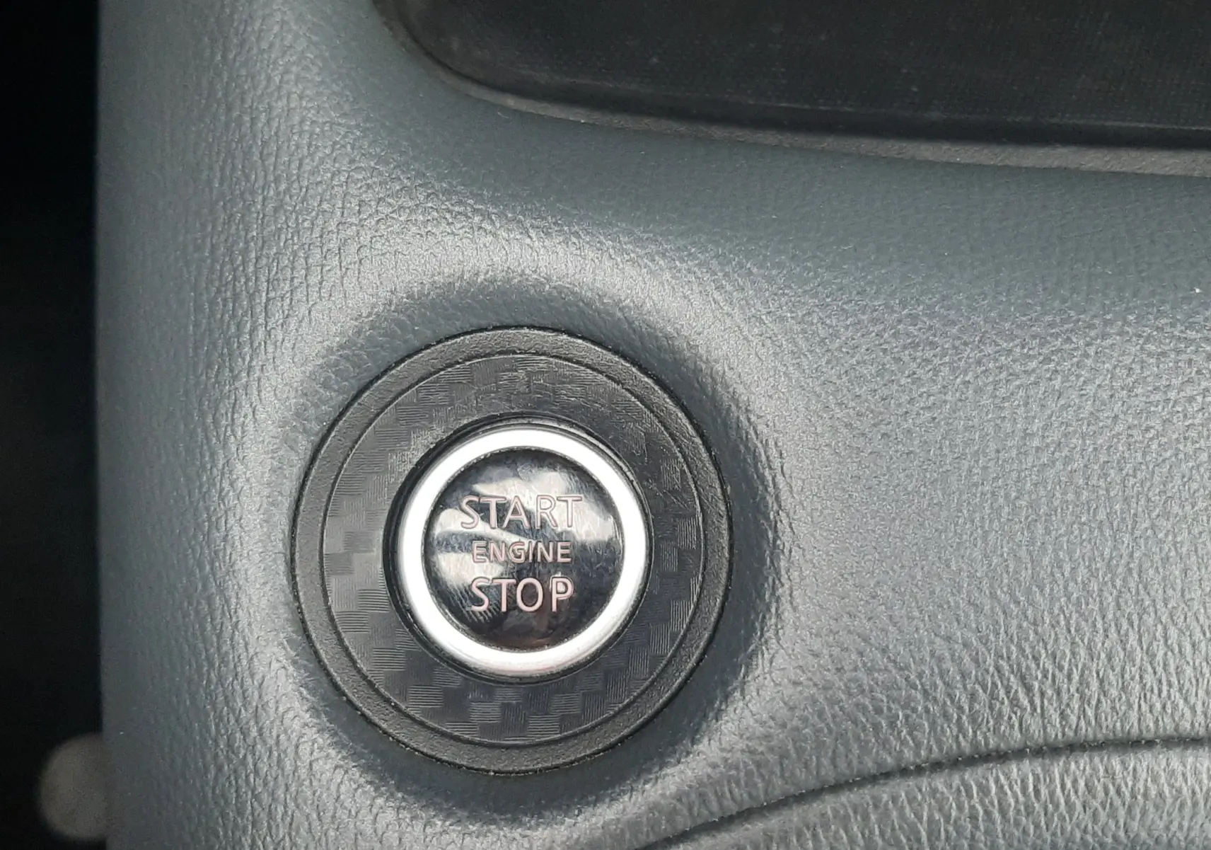 Gros plan sur le bouton Start/Stop moteur dans l’habitacle noir d’un Nissan Juke gris 2020.